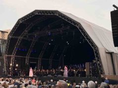 La ópera conquista las calles de ’s-Hertogenbosch con sonido ARA Opera al aire libre con sonido ARA en el corazón de ’s-Hertogenbosch Opera op de Parade reunió a miles de personas en la Parade de ’s-Hertogenbosch, en el sur de Países Bajos, para disfrutar de dos noches de ópera y música clásica al aire libre. El festival, organizado por Opera Zuid, Philzuid y Theater aan de Parade, regresó en 2026 con una edición especial marcada por su 20 aniversario y por una programación concebida para acercar la ópera a públicos muy diversos. La primera jornada estuvo dedicada a la Opera Singalong, una propuesta participativa en la que el público no solo asistió como espectador, sino que formó parte de la experiencia cantando junto a Philzuid, solistas de la International Vocal Competition ’s-Hertogenbosch y Brabant Koor. La segunda noche tuvo como protagonista L’Étoile, la ópera de Emmanuel Chabrier, una obra de carácter satírico, llena de humor y giros inesperados, que transformó la plaza en un gran teatro al aire libre. Para esta edición, la producción técnica estuvo a cargo de Tintaan, con Marty Brugmans como responsable de producción. Jannes Noorman se encargó de la mezcla de FOH, mientras que Miguel Augusto asumió la configuración y optimización del sistema. La solución de sonido se articuló a través de Unlimited Vision & Sound, empresa neerlandesa especializada en soluciones audiovisuales para eventos, con el apoyo de TSL Production y LSP, que aportaron parte del sistema utilizado para la producción. La coordinación local contó además con la implicación del equipo DAS AUDIO Benelux, con Henri y Rob desempeñando un papel clave en el seguimiento del proyecto, la conexión entre los diferentes equipos y el apoyo necesario para que la solución respondiera a las necesidades reales del evento. Reto: claridad, cobertura y control en un entorno abierto El principal reto técnico era trasladar la precisión de una producción operística a un espacio urbano abierto, con un público distribuido en una plaza amplia y sin las condiciones acústicas controladas de un teatro. En un evento de estas características, la cobertura debe ser uniforme, la inteligibilidad vocal resulta crítica y el sistema debe mantener la naturalidad de las voces y de la orquesta sin alterar la dinámica propia de la interpretación. A estas exigencias se sumaba la propia naturaleza del festival. La Opera Singalong requería un sistema capaz de acompañar una experiencia participativa, con miles de asistentes cantando y siguiendo la música en directo, mientras que L’Étoile exigía una reproducción más teatral, con mayor atención al detalle vocal, a los matices orquestales y a la integración entre música, escena y espacio. El entorno de la Parade, en pleno centro de ’s-Hertogenbosch, añadía además una necesidad clave: controlar con precisión la energía proyectada fuera del área de audiencia. En una producción al aire libre y en un contexto urbano, no basta con alcanzar presión sonora suficiente. Es necesario dirigir el sonido hacia el público, reducir la energía no deseada sobre el escenario y limitar la propagación hacia las zonas próximas de la ciudad. Solución: una configuración cardioide ARA para una experiencia operística al aire libre Para responder a estas necesidades, el sistema principal se configuró con 26 MARA, apoyados por 12 LARA-SUB y 10 ARA-P28. La elección de MARA y LARA-SUB resultó especialmente relevante por su diseño cardioide, que permitió mejorar el control de la directividad tanto en medias y bajas frecuencias como en el rango grave del sistema. En un evento al aire libre, esta capacidad de control aporta ventajas muy concretas. Por un lado, reduce la energía proyectada hacia la parte posterior del sistema, disminuyendo el nivel de sonido sobre el escenario y facilitando el trabajo de artistas, músicos y equipo técnico. Por otro, ayuda a contener la dispersión sonora hacia el entorno urbano, algo especialmente importante en una plaza situada en el centro de la ciudad. Los sistemas MARA proporcionaron la base principal de cobertura para la audiencia, con una respuesta diseñada para mantener claridad, definición y consistencia en un formato compacto, pero con la misma filosofía de control de la serie ARA. Su comportamiento permitió cubrir una audiencia amplia con una dispersión horizontal especialmente uniforme, manteniendo una experiencia sonora coherente en diferentes zonas de la plaza. Los LARA-SUB aportaron el refuerzo en bajas frecuencias necesario para sostener la dimensión musical del evento, manteniendo un comportamiento cardioide que contribuyó a reducir la energía no deseada detrás del sistema y a mejorar la limpieza general de la mezcla. Los ARA-P28 completaron la configuración para reforzar zonas específicas de cobertura y mejorar la experiencia del público en áreas donde era necesario un apoyo adicional. La combinación de estos sistemas permitió adaptar la respuesta a las características de la Parade, manteniendo un equilibrio entre presión sonora, inteligibilidad, naturalidad tímbrica y control de la dispersión. La coordinación entre Tintaan, Unlimited Vision & Sound, TSL Production, LSP y el equipo técnico de DAS AUDIO permitió implementar una solución ajustada a las necesidades reales del evento. El trabajo de Miguel Augusto como técnico de sistema fue clave para optimizar la configuración, ajustar la cobertura y garantizar que el sistema respondiera de forma precisa tanto durante la Opera Singalong como en la representación de L’Étoile. Conclusión: “Lo que más nos sorprendió fue la dispersión horizontal del sistema” La respuesta del sistema superó las expectativas del equipo técnico y de producción, que destacó especialmente la claridad, el control y la naturalidad conseguidos en una plaza abierta y en pleno entorno urbano. “Lo que más nos sorprendió fue la dispersión horizontal del sistema. En una plaza abierta, con una audiencia distribuida de forma muy amplia, necesitábamos una cobertura consistente, natural y bien controlada. El sistema consiguió mantener esa sensación de uniformidad sin perder definición ni generar más energía de la necesaria fuera del área de audiencia”, señaló Marty Brugmans, responsable de producción de Tintaan. Desde FOH, Jannes Noorman también valoró la respuesta del sistema durante las dos jornadas del festival. “Para ópera al aire libre, la inteligibilidad y la dinámica son fundamentales. El sistema ofreció una imagen muy estable, con voces claras, una respuesta musical muy natural y un escenario más limpio de lo habitual en este tipo de producciones”, explicó. La edición 2026 de Opera op de Parade demostró cómo una configuración basada en la serie ARA puede trasladar la precisión de una producción escénica a un espacio urbano abierto, manteniendo el equilibrio entre cobertura, control, reducción de energía no deseada y calidad sonora. La colaboración entre Theater aan de Parade, Unlimited Vision & Sound, Tintaan, TSL Production, LSP, Rob Pigmans y el equipo DAS AUDIO Benelux hizo posible una experiencia en la que la ópera se vivió de forma cercana, participativa y con un alto nivel técnico. Créditos del proyecto Evento: Opera op de Parade Producción: Tintaan Responsable de producción: Marty Brugmans FOH: Jannes Noorman Técnico de sistema: Miguel Augusto Sistema: DAS AUDIO Rental partners: TSL Production y LSP Coordinación local: DAS AUDIO Benelux, Henri y Rob Con la colaboración de: Theater aan de Parade, Unlimited Vision & Sound y Rob Pigmans