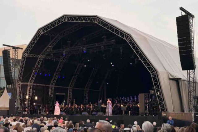 Opera al aire libre con sonido ARA en el corazón de ’s-Hertogenbosch Opera op de Parade reunió a miles de personas en la Parade de ’s-Hertogenbosch, en el sur de Países Bajos, para disfrutar de dos noches de ópera y música clásica al aire libre. El festival, organizado por Opera Zuid, Philzuid y Theater aan de Parade, regresó en 2026 con una edición especial marcada por su 20 aniversario y por una programación concebida para acercar la ópera a públicos muy diversos. La primera jornada estuvo dedicada a la Opera Singalong, una propuesta participativa en la que el público no solo asistió como espectador, sino que formó parte de la experiencia cantando junto a Philzuid, solistas de la International Vocal Competition ’s-Hertogenbosch y Brabant Koor. La segunda noche tuvo como protagonista L’Étoile, la ópera de Emmanuel Chabrier, una obra de carácter satírico, llena de humor y giros inesperados, que transformó la plaza en un gran teatro al aire libre. Para esta edición, la producción técnica estuvo a cargo de Tintaan, con Marty Brugmans como responsable de producción. Jannes Noorman se encargó de la mezcla de FOH, mientras que Miguel Augusto asumió la configuración y optimización del sistema. La solución de sonido se articuló a través de Unlimited Vision & Sound, empresa neerlandesa especializada en soluciones audiovisuales para eventos, con el apoyo de TSL Production y LSP, que aportaron parte del sistema utilizado para la producción. La coordinación local contó además con la implicación del equipo DAS AUDIO Benelux, con Henri y Rob desempeñando un papel clave en el seguimiento del proyecto, la conexión entre los diferentes equipos y el apoyo necesario para que la solución respondiera a las necesidades reales del evento. Reto: claridad, cobertura y control en un entorno abierto El principal reto técnico era trasladar la precisión de una producción operística a un espacio urbano abierto, con un público distribuido en una plaza amplia y sin las condiciones acústicas controladas de un teatro. En un evento de estas características, la cobertura debe ser uniforme, la inteligibilidad vocal resulta crítica y el sistema debe mantener la naturalidad de las voces y de la orquesta sin alterar la dinámica propia de la interpretación. A estas exigencias se sumaba la propia naturaleza del festival. La Opera Singalong requería un sistema capaz de acompañar una experiencia participativa, con miles de asistentes cantando y siguiendo la música en directo, mientras que L’Étoile exigía una reproducción más teatral, con mayor atención al detalle vocal, a los matices orquestales y a la integración entre música, escena y espacio. El entorno de la Parade, en pleno centro de ’s-Hertogenbosch, añadía además una necesidad clave: controlar con precisión la energía proyectada fuera del área de audiencia. En una producción al aire libre y en un contexto urbano, no basta con alcanzar presión sonora suficiente. Es necesario dirigir el sonido hacia el público, reducir la energía no deseada sobre el escenario y limitar la propagación hacia las zonas próximas de la ciudad. Solución: una configuración cardioide ARA para una experiencia operística al aire libre Para responder a estas necesidades, el sistema principal se configuró con 26 MARA, apoyados por 12 LARA-SUB y 10 ARA-P28. La elección de MARA y LARA-SUB resultó especialmente relevante por su diseño cardioide, que permitió mejorar el control de la directividad tanto en medias y bajas frecuencias como en el rango grave del sistema. En un evento al aire libre, esta capacidad de control aporta ventajas muy concretas. Por un lado, reduce la energía proyectada hacia la parte posterior del sistema, disminuyendo el nivel de sonido sobre el escenario y facilitando el trabajo de artistas, músicos y equipo técnico. Por otro, ayuda a contener la dispersión sonora hacia el entorno urbano, algo especialmente importante en una plaza situada en el centro de la ciudad. Los sistemas MARA proporcionaron la base principal de cobertura para la audiencia, con una respuesta diseñada para mantener claridad, definición y consistencia en un formato compacto, pero con la misma filosofía de control de la serie ARA. Su comportamiento permitió cubrir una audiencia amplia con una dispersión horizontal especialmente uniforme, manteniendo una experiencia sonora coherente en diferentes zonas de la plaza. Los LARA-SUB aportaron el refuerzo en bajas frecuencias necesario para sostener la dimensión musical del evento, manteniendo un comportamiento cardioide que contribuyó a reducir la energía no deseada detrás del sistema y a mejorar la limpieza general de la mezcla. Los ARA-P28 completaron la configuración para reforzar zonas específicas de cobertura y mejorar la experiencia del público en áreas donde era necesario un apoyo adicional. La combinación de estos sistemas permitió adaptar la respuesta a las características de la Parade, manteniendo un equilibrio entre presión sonora, inteligibilidad, naturalidad tímbrica y control de la dispersión. La coordinación entre Tintaan, Unlimited Vision & Sound, TSL Production, LSP y el equipo técnico de DAS AUDIO permitió implementar una solución ajustada a las necesidades reales del evento. El trabajo de Miguel Augusto como técnico de sistema fue clave para optimizar la configuración, ajustar la cobertura y garantizar que el sistema respondiera de forma precisa tanto durante la Opera Singalong como en la representación de L’Étoile. Conclusión: “Lo que más nos sorprendió fue la dispersión horizontal del sistema” La respuesta del sistema superó las expectativas del equipo técnico y de producción, que destacó especialmente la claridad, el control y la naturalidad conseguidos en una plaza abierta y en pleno entorno urbano. “Lo que más nos sorprendió fue la dispersión horizontal del sistema. En una plaza abierta, con una audiencia distribuida de forma muy amplia, necesitábamos una cobertura consistente, natural y bien controlada. El sistema consiguió mantener esa sensación de uniformidad sin perder definición ni generar más energía de la necesaria fuera del área de audiencia”, señaló Marty Brugmans, responsable de producción de Tintaan. Desde FOH, Jannes Noorman también valoró la respuesta del sistema durante las dos jornadas del festival. “Para ópera al aire libre, la inteligibilidad y la dinámica son fundamentales. El sistema ofreció una imagen muy estable, con voces claras, una respuesta musical muy natural y un escenario más limpio de lo habitual en este tipo de producciones”, explicó. La edición 2026 de Opera op de Parade demostró cómo una configuración basada en la serie ARA puede trasladar la precisión de una producción escénica a un espacio urbano abierto, manteniendo el equilibrio entre cobertura, control, reducción de energía no deseada y calidad sonora. La colaboración entre Theater aan de Parade, Unlimited Vision & Sound, Tintaan, TSL Production, LSP, Rob Pigmans y el equipo DAS AUDIO Benelux hizo posible una experiencia en la que la ópera se vivió de forma cercana, participativa y con un alto nivel técnico. Créditos del proyecto Evento: Opera op de Parade Producción: Tintaan Responsable de producción: Marty Brugmans FOH: Jannes Noorman Técnico de sistema: Miguel Augusto Sistema: DAS AUDIO Rental partners: TSL Production y LSP Coordinación local: DAS AUDIO Benelux, Henri y Rob Con la colaboración de: Theater aan de Parade, Unlimited Vision & Sound y Rob Pigmans