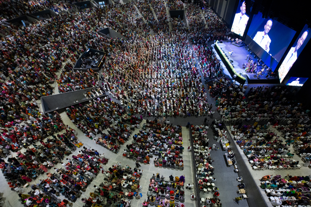 El espacio, con capacidad para 25.000 personas, incorpora una consola grandMA3 light para gestionar alrededor de 180 luminarias en producciones en directo, servicios religiosos y retransmisiones audiovisuales. El New Life Assembly of God (NLAG) Worship Center, situado en Chennai, al sur de la India, ha incorporado una consola grandMA3 light de MA Lighting como sistema principal de control de iluminación de sus nuevas instalaciones. El recinto multifuncional, con capacidad para 25.000 asistentes, está diseñado para acoger servicios religiosos, conciertos, conferencias y producciones audiovisuales de gran formato. El proyecto, dirigido por el pastor ejecutivo Benjamin Mohan, planteaba la necesidad de disponer de una plataforma de control flexible, fiable y preparada para futuras ampliaciones. Entre los requisitos principales se encontraban la posibilidad de almacenar y recuperar escenas y programaciones de forma consistente, así como gestionar diferentes configuraciones de iluminación en función de las características de cada evento. La instalación cuenta con aproximadamente 180 luminarias distribuidas en cinco estructuras truss, controladas mediante múltiples universos DMX. La infraestructura combina la consola grandMA3 light con nodos de red de terceros y 28 distribuidores DMX, formando un sistema que centraliza la programación, la reproducción de secuencias, la ejecución de cues y los eventos sincronizados mediante código de tiempo. Un sistema de control adaptable a diferentes producciones La configuración diáfana del recinto permite modificar la disposición del escenario y del público según las necesidades de cada celebración o producción. Esta versatilidad exige un sistema de iluminación capaz de adaptarse a distintos equipos técnicos, operadores y formatos de espectáculo. Según explica Theophorus Samuel, director de iluminación de NLAG, una de las características determinantes para seleccionar grandMA3 fue su capacidad de trabajo multiusuario. Esta funcionalidad permite que varios operadores y voluntarios trabajen simultáneamente sobre un mismo archivo de espectáculo, facilitando la coordinación durante la preparación y ejecución de los eventos. La arquitectura de red se ha diseñado teniendo en cuenta la escalabilidad, la redundancia y la continuidad operativa, tanto en los servicios habituales como en las producciones de mayor complejidad. En cuanto a la distribución de las luminarias, la primera estructura truss incorpora principalmente proyectores de perfil destinados a la iluminación principal del escenario y a aplicaciones específicas. Las cuatro restantes combinan cabezas móviles wash, spot y luminarias blinder. Samuel señala que el objetivo durante los servicios habituales es crear un entorno inmersivo y confortable, evitando efectos excesivos que puedan distraer a los asistentes. La iluminación debe acompañar el desarrollo de cada celebración y contribuir a la experiencia visual sin adquirir un protagonismo innecesario. Esta filosofía también responde a la creciente importancia de las retransmisiones televisivas y el streaming en los centros religiosos del sur de la India, donde la iluminación escénica desempeña un papel cada vez más relevante en la calidad de las producciones audiovisuales. Programación colaborativa y visualización 3D La elección de grandMA3 supuso un cambio respecto a los sistemas de control utilizados anteriormente por NLAG en sus otras instalaciones de Chennai. Durante la fase de diseño del nuevo recinto, las consultoras Salas O'Brien y HouseRight desarrollaron los conceptos audiovisuales, acústicos y los diseños esquemáticos en colaboración con el estudio internacional de arquitectura Populous y el equipo de NLAG. HouseRight propuso inicialmente la incorporación de grandMA3, una recomendación que posteriormente fue evaluada por Benjamin Mohan y Theophorus Samuel. En el desarrollo y la implementación del proyecto también participaron Franco Zaghini, director de desarrollo de negocio de MA Lighting, el diseñador de iluminación local Viju y Manuel Raj, director de medios de NLAG. Uno de los aspectos más valorados por el equipo técnico es la integración de grandMA3 con los formatos GDTF y MVR, utilizados para la gestión de perfiles de luminarias, las copias de seguridad y la preparación de entornos de previsualización tridimensional. Esta compatibilidad facilita la correspondencia entre la programación y la representación virtual de los equipos, además de simplificar la preparación de diferentes configuraciones de espectáculo. Samuel destaca igualmente las herramientas de programación Recipes, Cues y Sequences, que permiten realizar modificaciones sobre múltiples luminarias y actualizar contenidos sin necesidad de reconstruir por completo los espectáculos. Estas funciones resultan especialmente útiles en un recinto que trabaja con diferentes equipos de producción y operadores voluntarios. Los recursos de ayuda integrados en grandMA3 también contribuyen a la formación de nuevos usuarios y a la resolución de incidencias durante la operación. Soporte técnico y puesta en marcha La consola grandMA3 light fue suministrada por Hi-Tech Audio & Image, distribuidor oficial de MA Lighting en India, que también proporcionó asistencia técnica durante el proyecto. Con el nuevo sistema en funcionamiento, NLAG dispone de una infraestructura de control preparada para gestionar tanto sus servicios semanales como conciertos, encuentros juveniles, representaciones teatrales y otros eventos de gran formato. Para Benjamin Mohan, el resultado más importante es conseguir que todos los elementos técnicos funcionen de manera coordinada y que la tecnología contribuya a la experiencia de los asistentes sin interferir en el desarrollo de las celebraciones.